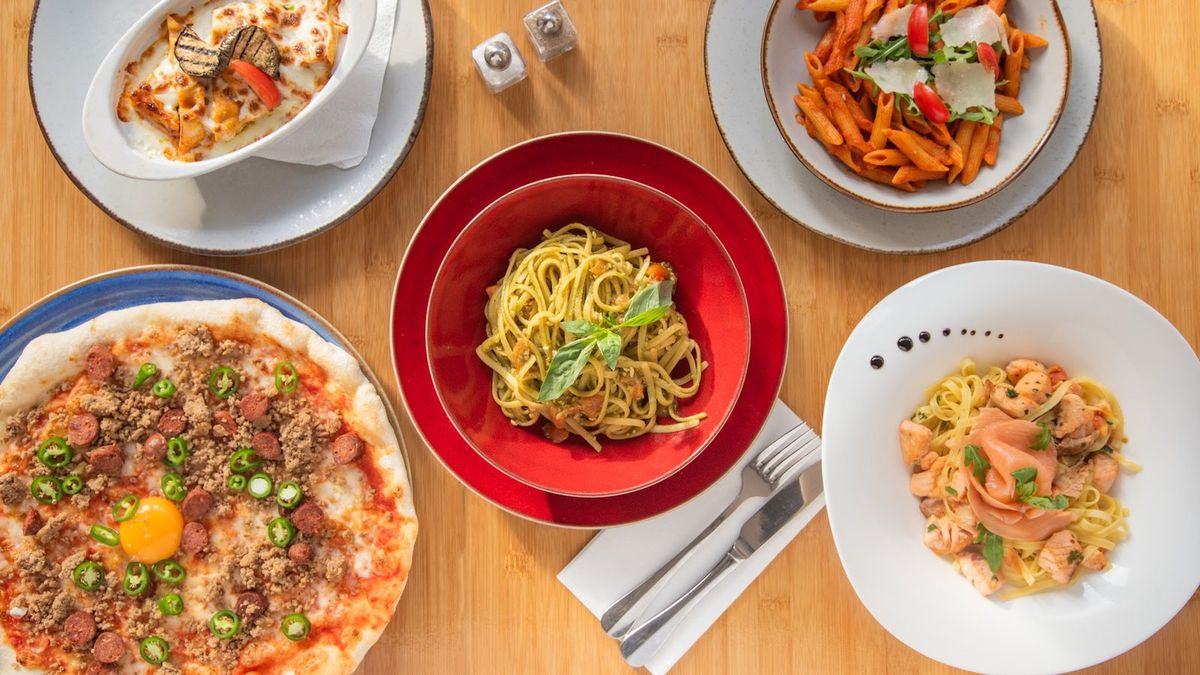 Lasagnes, linguine au pesto, penne, tagliatelles au saumon et pizza sur une table en bois
